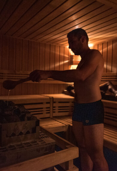 Personne qui ajoute de l'eau dans un sauna